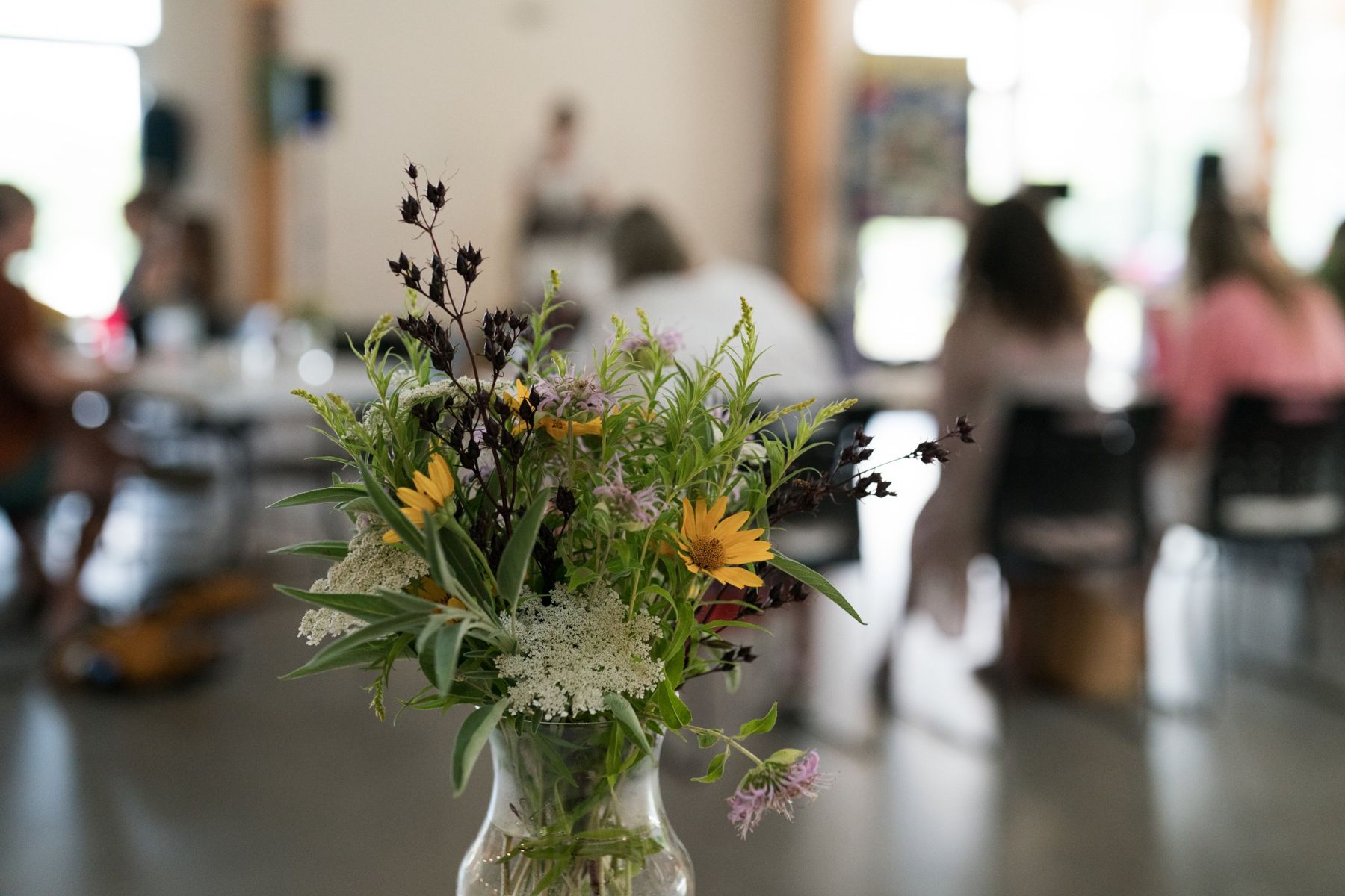 Wildflowers in a jar on a table, the audience soft behind